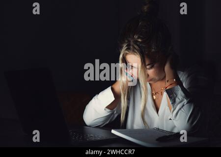 Überwältigter junger kaukasischer Student, der den Hals berührt, an schlechter Position leidet, die Rückenbrücke massiert, Schmerzen lindert, sich erschöpft fühlt, spät abends am Computer im Büro zu arbeiten. Stockfoto