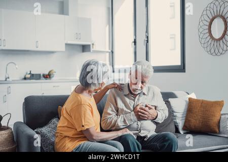 Grauhaariger Mann, der Brust berührt, Herzinfarkt hat, Schmerzen fühlt, an Herzschmerzkrankheit zu Hause leidet, reife Frau unterstützt, ihn umarmen, Familie mittleren Alters, horizontales Banner, Nahaufnahme Stockfoto