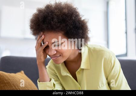 Verärgert gestresste junge afrikanische Frau Massage Schläfen fühlen starke Kopfschmerzen Konzept, frustrierte müde schwarze Mädchen berühren schmerzenden Kopf leiden unter Migräne Bluthochdruck sitzend auf Sofa zu Hause Stockfoto