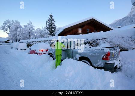 Der Mann befreit sein Auto bei laufendem Motor von Schneemassen Stockfoto