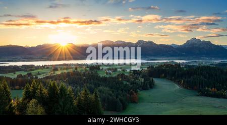 Sonnenaufgang über dem Forggensee bei Füssen. Schneebedeckte Ammergauer Alpen im Hintergrund. Bayern, Deutschland, Europa Stockfoto