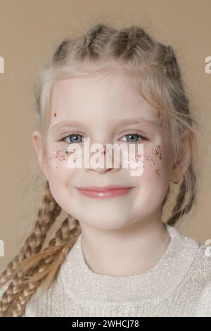 Porträt eines süßen kleinen blonden Mädchens mit Boxerflechten und Glitzern im Gesicht Stockfoto