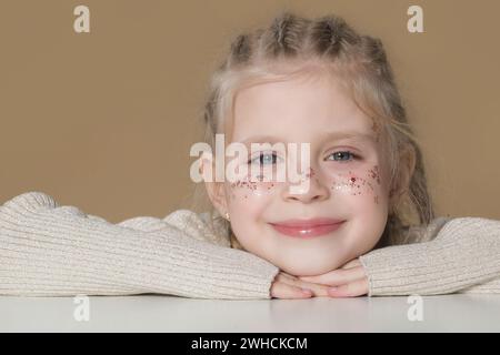 Porträt eines süßen kleinen blonden Mädchens mit Boxerflechten und Glitzern im Gesicht Stockfoto