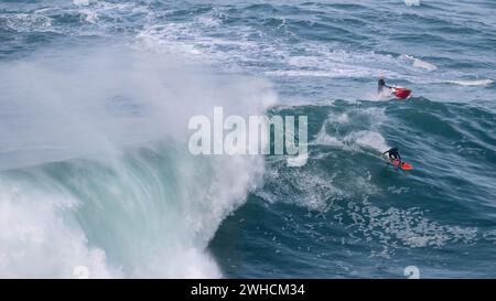 Ein Surfer und ein Jet Ski auf einer großen Welle, Nazare, Portugal Stockfoto