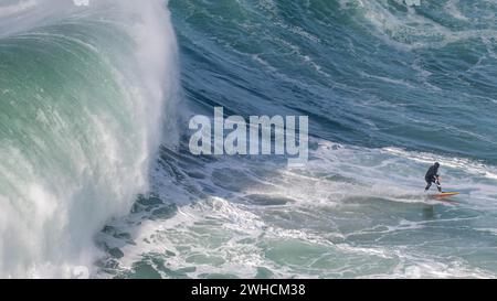 Ein Surfer reitet auf einer stürzenden Welle, Nazare, Portugal Stockfoto