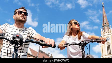 Ein junges Städtepaar reist mit dem Fahrrad durch die Stadt. Menschen, die Fahrrad fahren. Fahrradinfrastruktur in Serbien, Novi Sad. Stockfoto