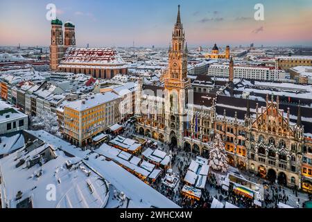 Schneebedeckter Marienplatz mit Weihnachtsmarkt, Weihnachtsmarkt, Rathaus und Türmen der Kirche unserer Lieben Frau in der Abendsonne, München, Oberen Stockfoto