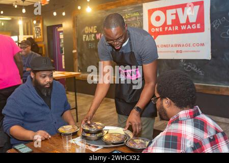 Detroit, Michigan, USA. Februar 2024. Der Gouverneur von Michigan, Garlin Gilchrist, verbrachte eine Stunde als Kellner im Yum Village Restaurant, um die Kampagne für einen fairen Lohn zu fördern. Ein fairer Lohn bedeutet einen lebensfähigen Mindestlohn für alle und die Abschaffung des Untermindestlohns für Arbeitnehmer mit Trinkgeld. Quelle: Jim West/Alamy Live News Stockfoto