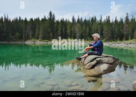 Wanderer, die auf einem Felsen im See ruhen, Valley of Five Lakes, Jasper National Park, Alberta, Kanada Stockfoto