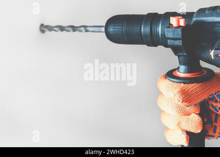 Arbeiter Hand mit einem Bohrhammer. Hände in Schutzhandschuhen mit Hammerbohrer-Perforator. Nahaufnahme Stockfoto