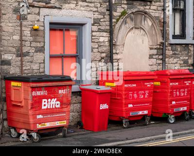 Rote „Biffa“-Abfalltonnen für das Recycling und die Entsorgung von Handelsabfällen befinden sich auf dem Bürgersteig außerhalb eines lokalen Unternehmens. Stockfoto