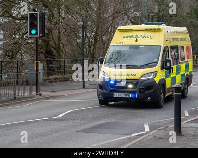 Ein schneller Krankenwagen mit blauen Lichtern überquert einen Pelikan-Fußgänger, der die Sandes Avenue in Kendal, Cumbria, Großbritannien, auf einem Notruf überquert. Stockfoto