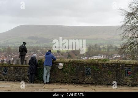 Eine ergreifende Szene, in der männliche und weibliche Blicke auf den Pendle Hill in der Ferne in der Nähe der Statue eines Soldaten an einem Kriegsdenkmal für die Gefallenen der 2. Weltkrieg werfen Stockfoto