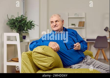 Porträt eines alten Mannes im Ruhestand mit grauen Haaren, der auf dem Sofa sitzt Stockfoto