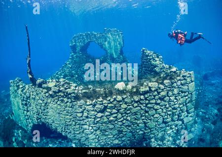 Taucher schwimmt durch eine versunkene Mühle in einem See Stockfoto