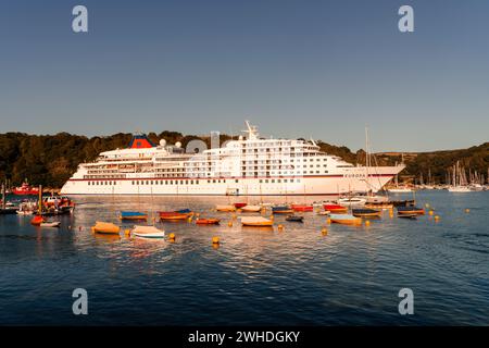 Das Kreuzfahrtschiff Europa liegt an einem Sommerabend im Hafen von Fowey Bay in Cornwall, umgeben von kleinen Booten Stockfoto