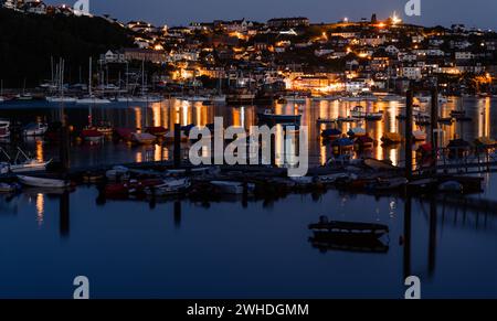 Blick auf den beleuchteten Hafen in der Bucht von Fowey in Cornwall, Großbritannien, spiegelt sich die Stadt im ruhigen Wasser wider Stockfoto