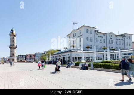 Der alte Leuchtturm als Wahrzeichen im Stadtblick mit Hotel an der öffentlichen Strandpromenade in Warnemünde, Hansestadt Rostock, Ostseeküste, Mecklenburg-Vorpommern, Deutschland, Europa Stockfoto