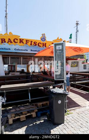 Blick von der Promenade am Alten Strom zu einem Fischerboot mit frittiertem Fisch in Warnemünde, Hansestadt Rostock, Ostseeküste, Mecklenburg-Vorpommern, Deutschland, Europa Stockfoto