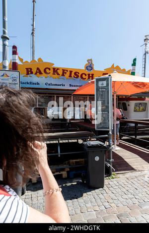 Blick von der Promenade am Alten Strom zu einem Fischerboot mit frittiertem Fisch in Warnemünde, Hansestadt Rostock, Ostseeküste, Mecklenburg-Vorpommern, Deutschland, Europa Stockfoto