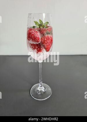 Frische rote Vollreife Erdbeeren mit Mineralwasser im Sektglas als alkoholfreies Erfrischungsgetränk im Sommer Stockfoto