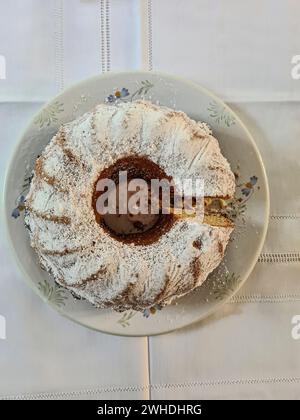 In Scheiben geschnittener Marmorkuchen mit Puderzucker auf einer weißen Tischdecke und einem Teller Stockfoto