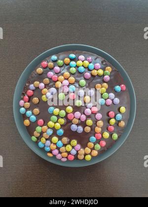 Schokoladenkuchen mit Smarties auf einem grauen Teller Stockfoto