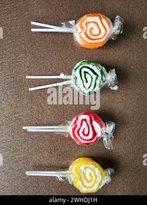 Vier Lollies liegen nebeneinander auf dem Holztisch Stockfoto