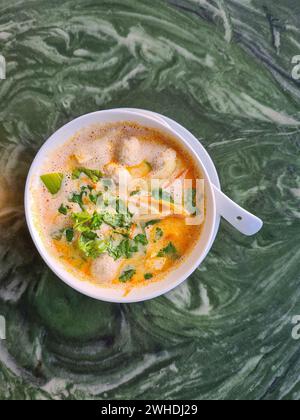 Tom Kha Gai, Hühnersuppe in einer weißen Schüssel, enthält die Zutaten Kokosmilch, Galgant, Zitronengras, Hühnchen, Lauch und Petersilie Stockfoto