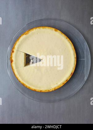 Runder, glatter, feuchter Käsekuchen mit einem Dreieck im Kuchen Stockfoto