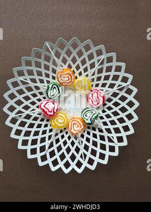 Acht Lollies sind noch immer in Plastikfolie im Kreis auf einer weißen Schüssel gewickelt Stockfoto