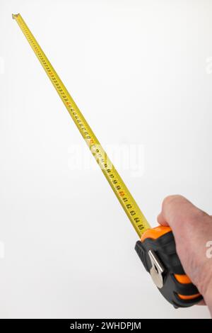 Männliche Hand, die ein gelbes Maßband mit Millimeter- und Zentimeterteilung hält, Messwerkzeug, weißer Hintergrund, Stockfoto