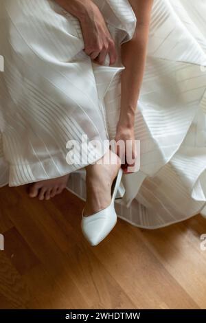 Braut zieht Schuhe an, Hochzeitskleid, Detail Stockfoto