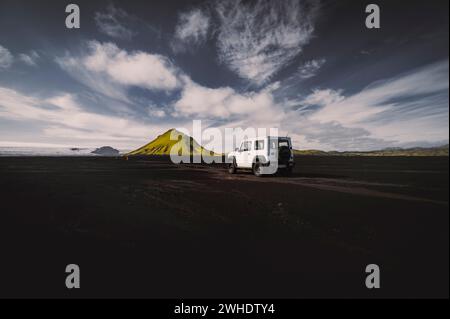 Off-road in an off-road vehicle in the southern highlands of Iceland on an endless plain of black volcanic rock. The extinct volcanic cone of Maelifell in the background Stockfoto