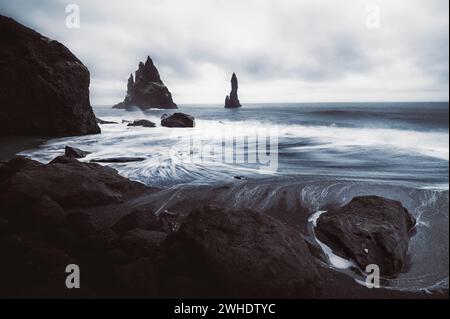 Reynisfjara Beach in Island. Schwarzer Sandstrand mit Basaltformationen. Langzeitbelichtung mit Wellen. Stockfoto