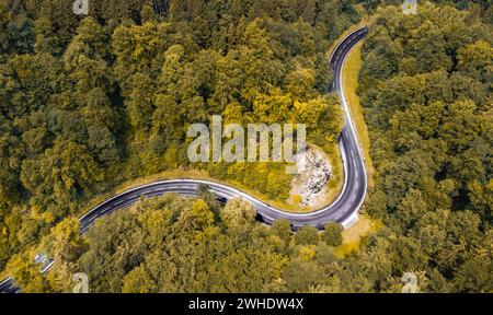 Luftaufnahme einer kurvenreichen Passstraße im Naturpark Altmühltal in Oberbayern. Die Straße schlängelt sich malerisch durch einen sommerlich gemischten Laubwald an einem Felsvorsprung vorbei Stockfoto