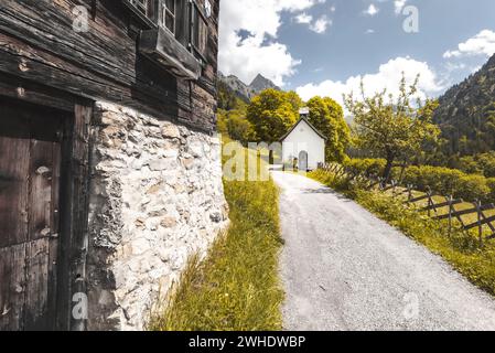 Allgäuer Bergbauerndorf im Frühjahr. Alte Berghütte mit kleiner Kapelle im Hintergrund. Bergbaudorf Gerstruben bei Oberstdorf vor dem Höfats. Allgäuer Alpen, Oberallgäu, Allgäu, Bayern, Süddeutschland, Deutschland Stockfoto