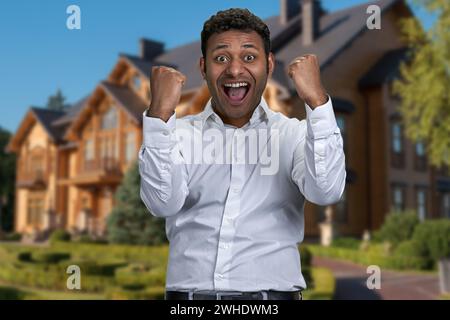Ein überfröhlicher junger Mann ballte seine Fäuste draußen. Zielerreichungskonzept. Stockfoto