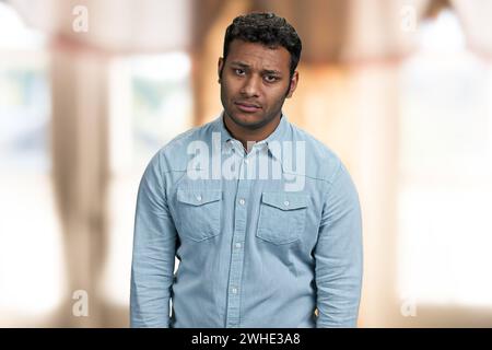 Porträt eines verärgerten jungen indianers, der in die Kamera schaut. Enttäuschter Kerl vor verschwommenem Hintergrund. Stockfoto