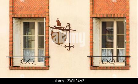 Einzigartige alte Fenster umgeben von Ziegeln mit Rollläden und einem Metallschild Stockfoto