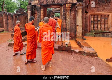 SIEM Reap, Camboda, 4. Juli 2019 - Kambodschanische Mönche mit leuchtend roten, umlaufenden und ockerfarbenen Reben im Banteay Srei Tempel aus dem 10. Jahrhundert, erbaut von Rajendravarman Stockfoto