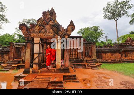 SIEM Reap, Camboda, 4. Juli 2019 - Kambodschanische Mönche mit leuchtend roten, umlaufenden und ockerfarbenen Reben im Banteay Srei Tempel aus dem 10. Jahrhundert, erbaut von Rajendravarman Stockfoto