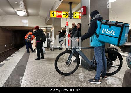 '06.12.2023, Deutschland, Berlin, Berlin - Mitarbeiter der Wolt-Lieferung wartet mit seinem Fahrrad auf die U-Bahn. 00S231206D188CAROEX.JPG [MODELL REL Stockfoto