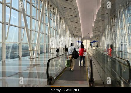 '11.12.2023, China, Hongkong, Hongkong - Reisende stehen auf einem Förderband im Terminal des internationalen Flughafens Hongkong. 00S231211D231CAROEX. Stockfoto