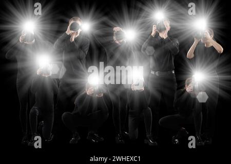 Gruppe von Fotografen mit Kameras auf schwarzem Hintergrund. Paparazzi machen Bilder mit Blitzen Stockfoto