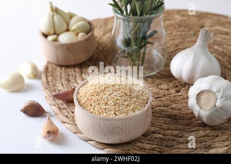 Getrocknete Knoblauchkörner in der Schüssel, frische Zwiebeln und Nelken auf weißem Tisch Stockfoto