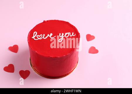 Bento Torte mit Text Love You und Papierherzen auf rosa Tisch, Platz für Text. St. Valentinstag-Überraschung Stockfoto