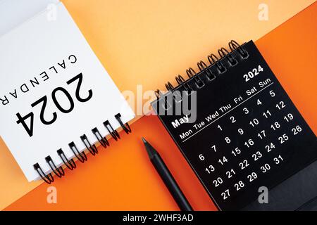 Mai 2024 Schreibtischkalender in Schwarz-weiß-Farbe mit Bleistift auf orangefarbenem Hintergrund. Stockfoto