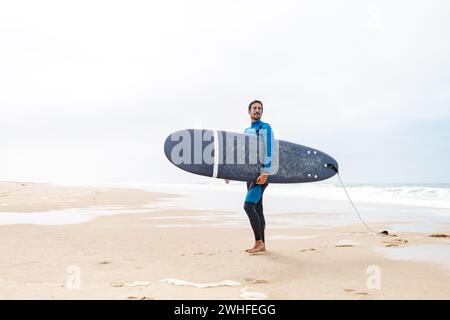 Junger männlicher Surfer im Neoprenanzug Stockfoto
