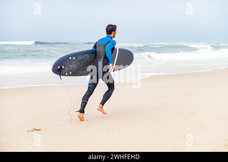 Junger männlicher Surfer im Neoprenanzug Stockfoto